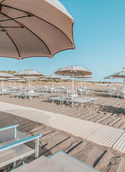 Spiaggia deserta con ombrelloni, cielo limpido e sabbia dorata.