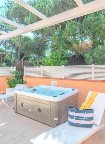 Terrace with hot tub and lounge chairs, surrounded by trees.