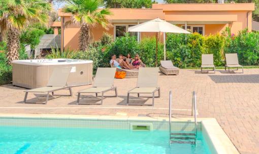 Pool with loungers and jacuzzi, relaxing setting.