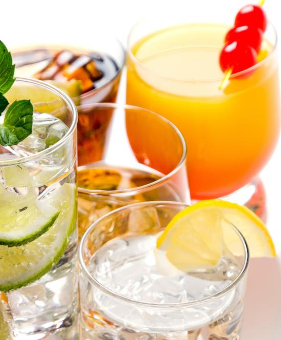Varietà di cocktail colorati con guarnizioni di frutta e ghiaccio.