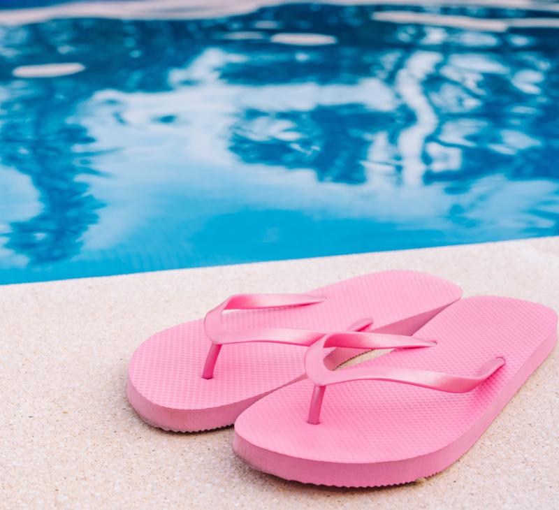 White slippers and towel on floating board in pool.