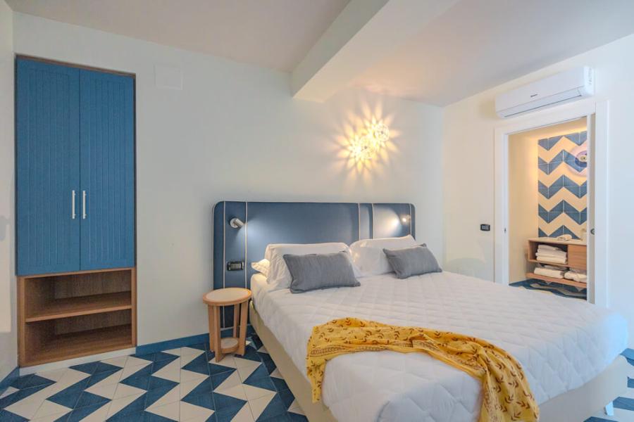 Modern room with double bed and ensuite bathroom, blue decorations.